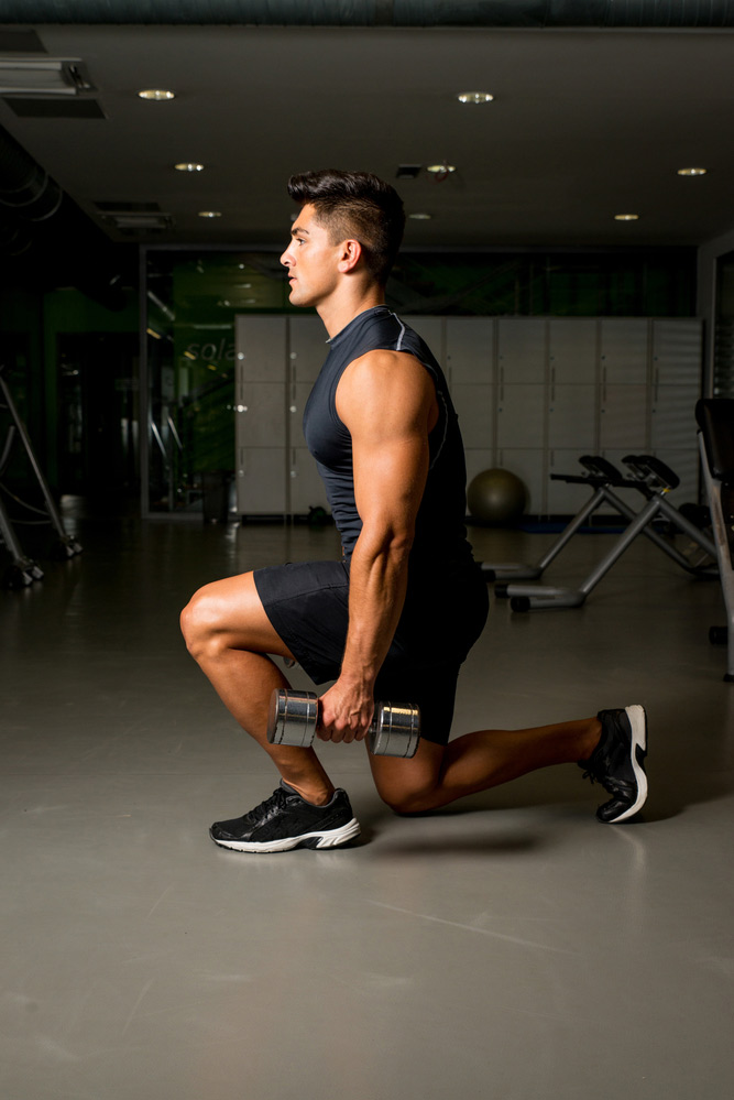performing a dumbbell lunge in your garage gym